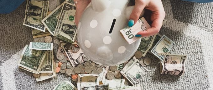 woman putting money into a spotted piggy bank