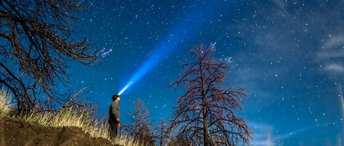 man with head flashlight looking up at the night sky i