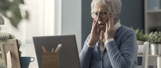 senior woman looking shocked at a computer screen